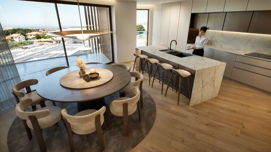 Cozinha com ilha e zona de refeições junto aos envidraçados