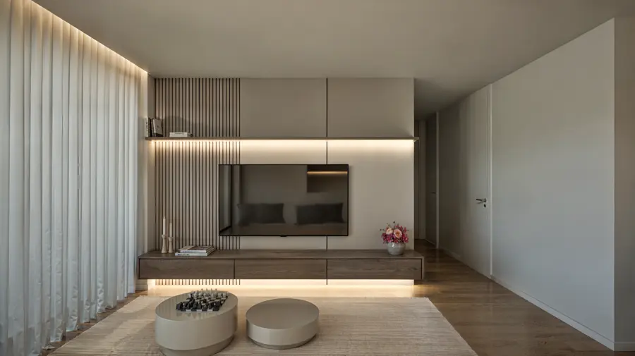 Sala com móvel de televisão em madeira e iluminação indireta